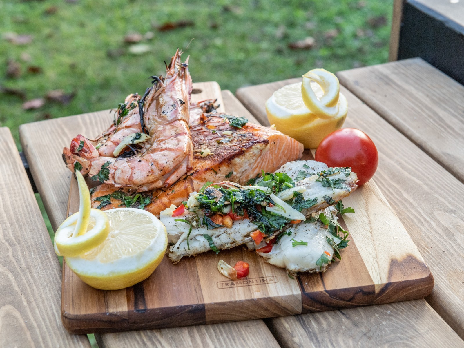 Gegrillte Lachs- und Fischfilets mit Riesengarnelen, Kräutern und Zitrone auf Holzbrett